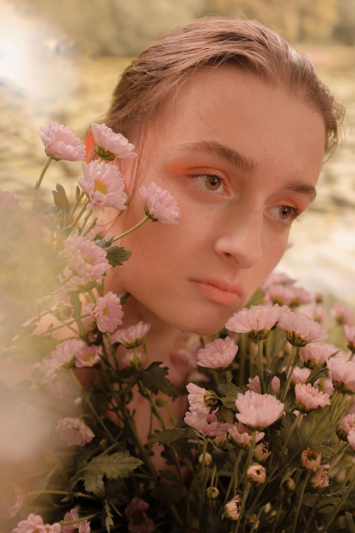 Natural portrait surrounded by pale pink flowers in soft daylight
